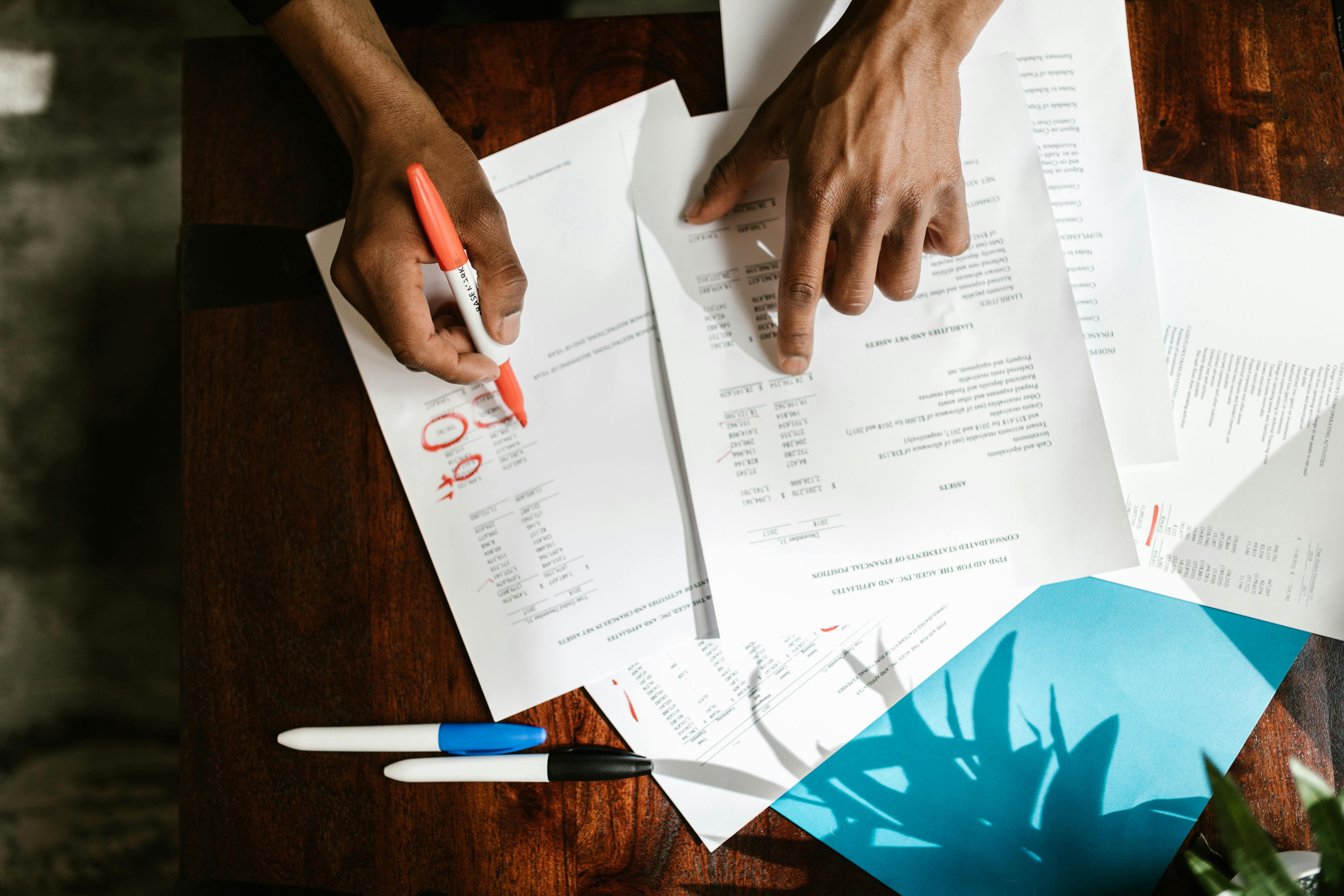 Overhead view of hands highlighting financial documents on a desk.